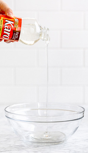 A hand pouring Karo Corn Syrup in to a glass bowl